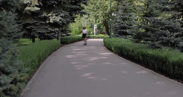 Young woman riding an electric scooter on the square area