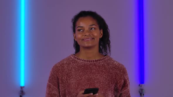 Portrait of Afro American Young Woman is Texting on Mobile and Rejoice