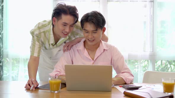 Young asian gay couple hugging and takes care of his boyfriend, surfing on internet during break