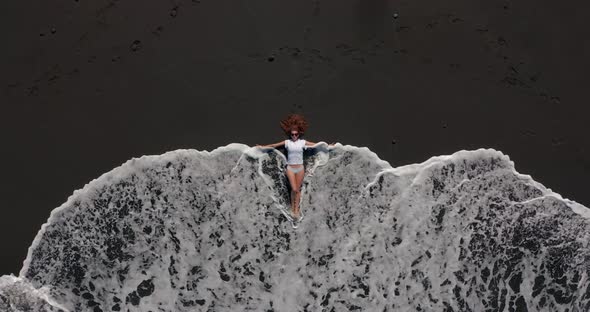 Aerial View. Beautiful Woman Lay Down and Rest on the Black Beach in Tenerife While a Long Oceanic