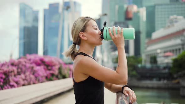 Young Asian Woman Drinking Water During Workout