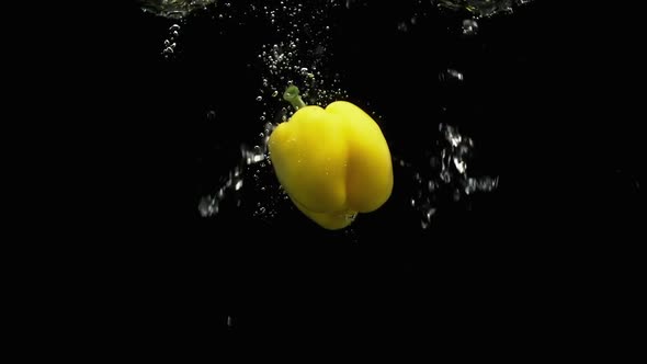 Yellow Bell Pepper Fall Into Water With Lot Of Air Bubbles And Water Splashes Black Background