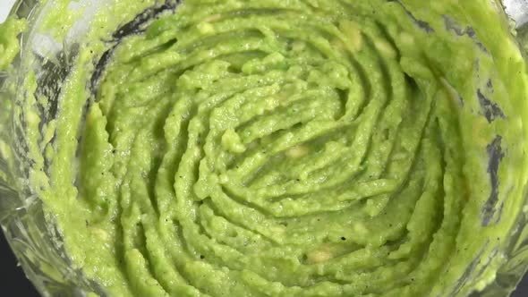Juicy guacamole dip rotating in glass bowl background. Cooking healthy food. Making avocado dip