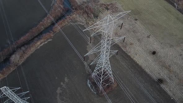 Aerial Drone Dolly Right - Pair of High Voltage Electrical Towers from Above - Winterish Landscape