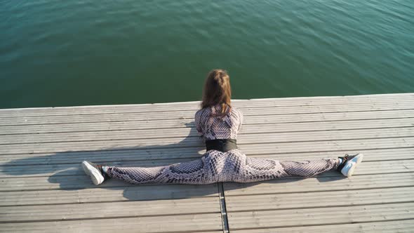 girl sitting in splits pier next beautiful lake Yoga and stretching in open air
