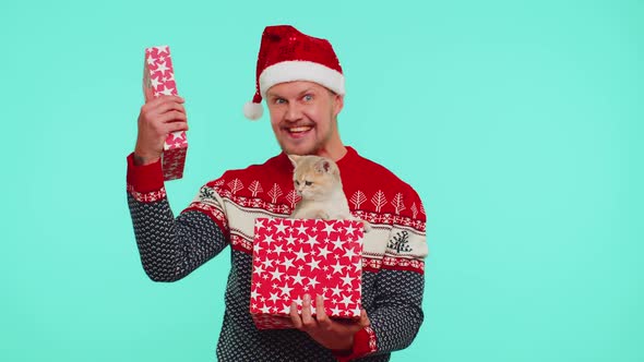 Funny 30s Years Old Man Wears Red New Year Sweater Hat Unwrapping Gift Opening Box with Pet Cat