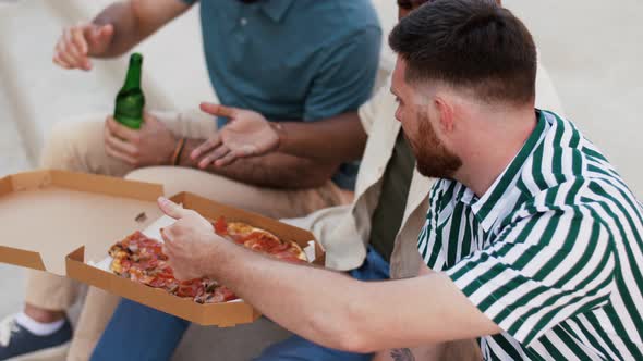 Male Friends Eating Pizza with Beer on Rooftop