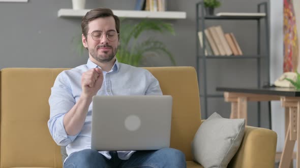 Young Man with Laptop Having Wrist Pain on Sofa