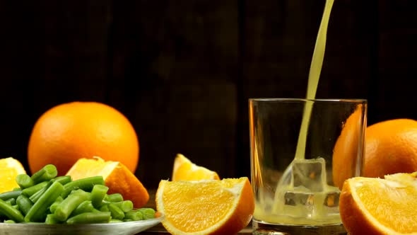 A Few Slices And A Whole Orange And Juice Are Poured Into A Glass And Green Beans