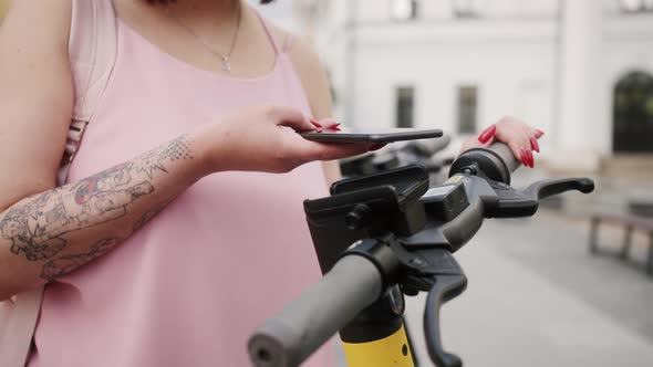 Person use mobile application for sharing or rental electric scooter.Close-up of hands holding phone