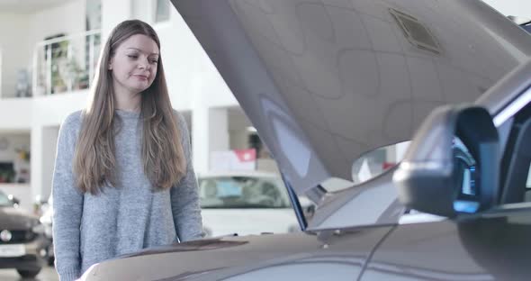 Portrait of Young Desperate Caucasian Woman Standing Next To Open Car Hood and Shaking Head