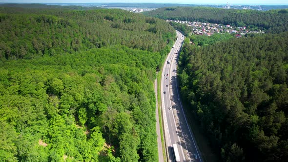 Traveling On The European Route Through Dense Green Forest In Gdynia, Poland. aerial tilt down