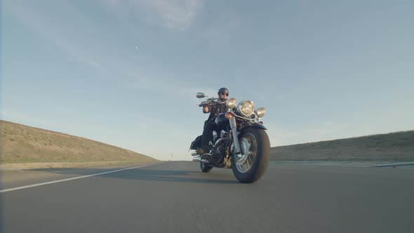 Biker is Driving Motorbike During Road Trip at Summer Sunset Time