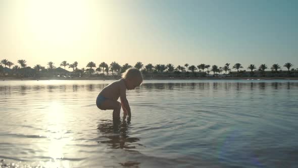 Sweet Active Toddler Falling Into Seawater at Summer Coastline.