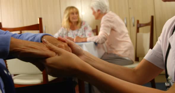 Doctor holding hands of a senior woman sitting in wheelchair