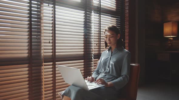 Young Asian Woman Browsing the Web on Laptop