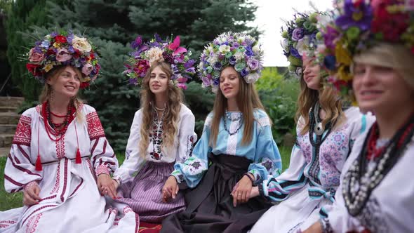 Positive Ukrainian Young Women Singing Sitting in National Clothing in Spring Summer Park