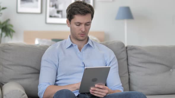 Handsome Young Man Browsing Internet on Tablet