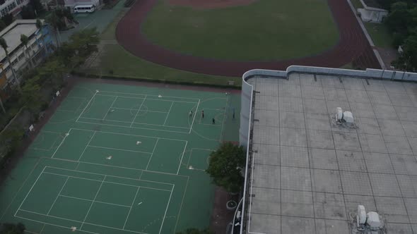 A drone shot of taiwanese kids playing basketball on a school field