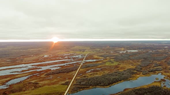 Aerial view of road in a field with lakes and forests at dawn in North Shoal Lake, Manitoba, Canada