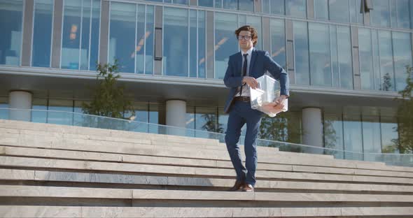 Sad Dismissed Caucasian Businessman Sitting on Stairs with Plastic Box