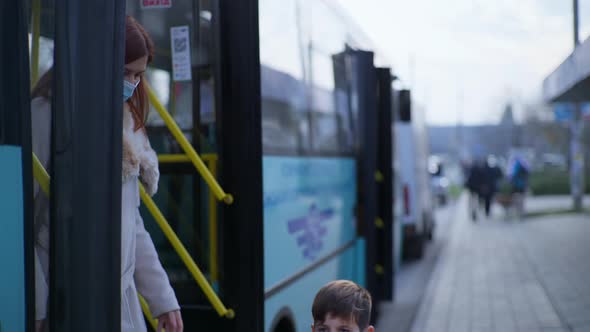 Boy and Mother Get Out of City Transport To Bus Stop and Happily Take Off Medical Mask From His Face