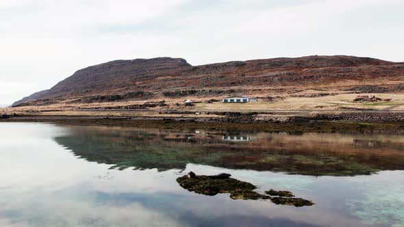 Remote Building And Mountain Landscape Reflected In Fjord