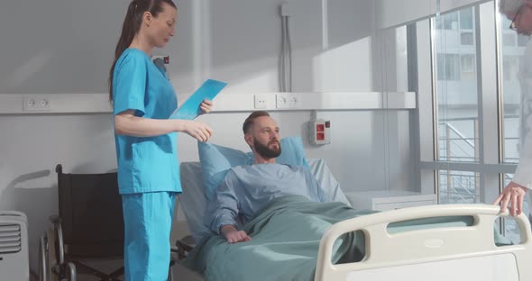 Doctor and Nurse Visiting Young Sick Man at Hospital