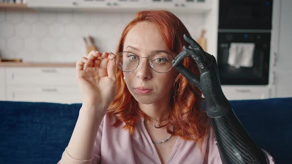 Young Redhaired Attractive Woman Putting on Glasses Using Bionic Prosthesis