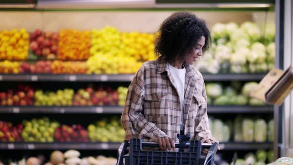 Cheerful Woman Walks Through Supermarket with Cart Taking a Pack of Potatoes