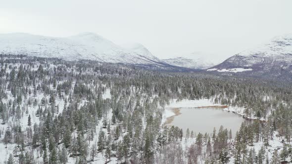 Thick Forest With Lake And Mountainscape In Background During Snowy Winter At Innlandet county, Dovr