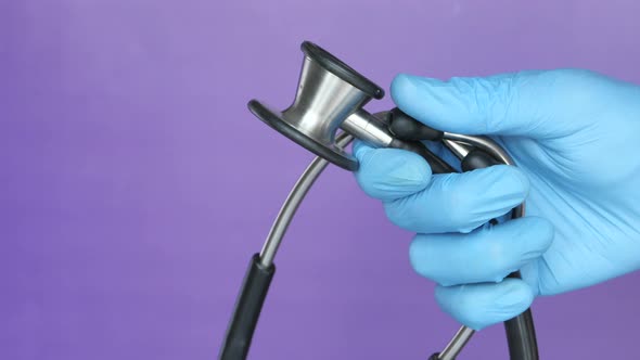 Doctor Hand with Medical Gloves Holding Stethoscope  alt