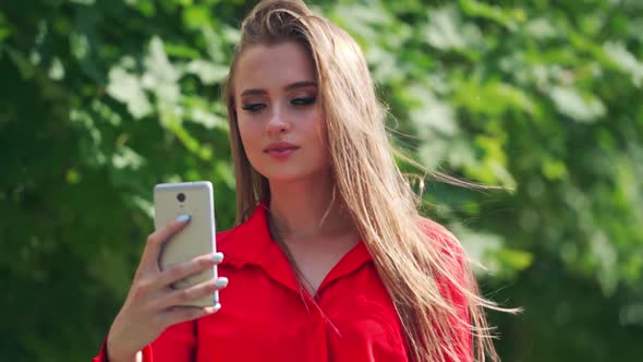 Beautiful woman doing selfie. Gorgeous young female in red dress photographing herself
