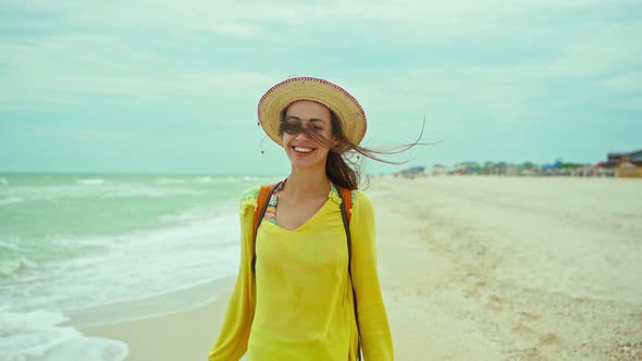 Joyful Woman in Hat Wearing Yellow Shirt Having Fun and Feeling Happiness on Beach with Waves