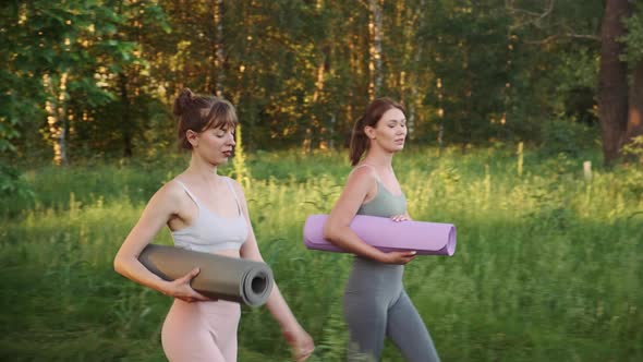 Two Young Fit Women with Sports Mats Go for Yoga Pilates or Fitness Training Outdoors