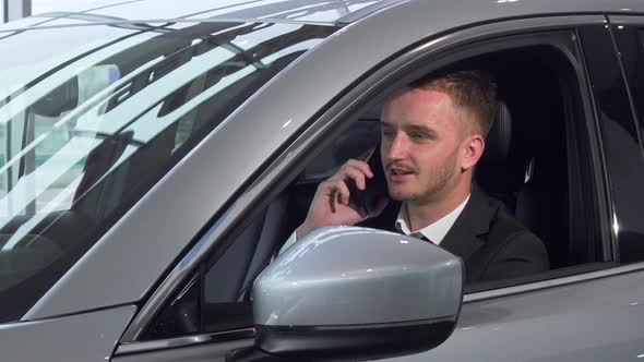 Businessman Talking on the Phone, Sitting in a New Automobile