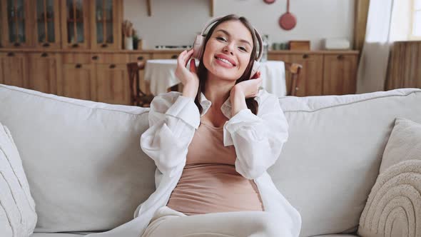 Glad Pregnant Woman in Headphones Listens to Popular Music