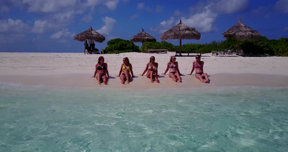 Modern happy ladies relaxing spending quality time at the beach on sunny blue and white sand background