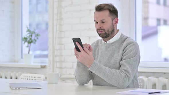 Successful Creative Man Using Smartphone in Office