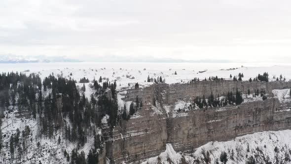 Drone flying up to snow covered mountain ridge