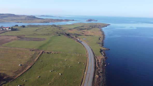 Road E39 along Norway coast is surrounded by green grasslands and going down into subsea tunnel Byfj