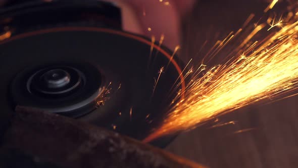 Man Sharpen Axe with Grinder in the Dark with Flying Sparks