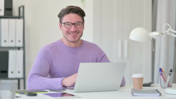 Middle Aged Man with Laptop Smiling at the Camera 