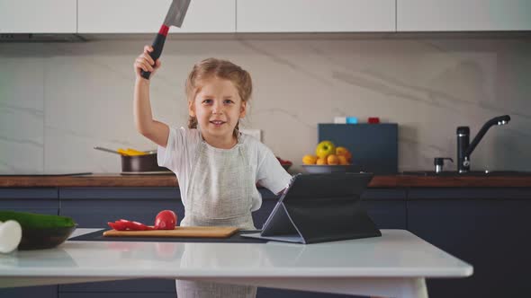 Girl with Long Hair in Kitchen in Apron Stands