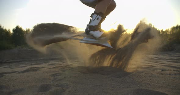SLOW MOTION Hipster Man Athlete in Shorts Tries Doing Tricks with a Board on Sand Dunes