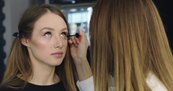 Closeup of Girl with Perfect Nude Makeup and Makeup Artist