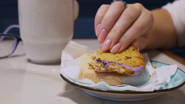 Closeup of a Woman's Hand with Wellgroomed Fingers Breaks Off a Piece of Sweet Oatmeal Cookies and