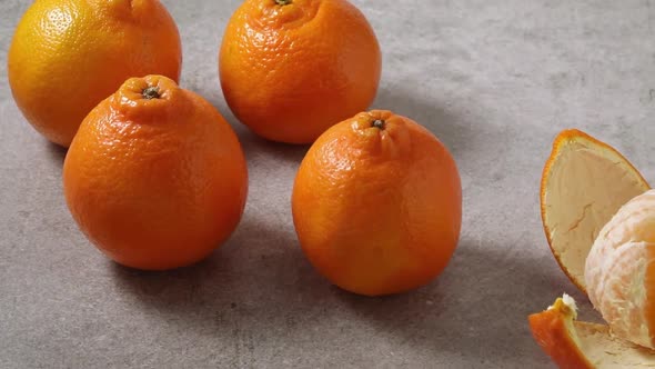 Fresh group of Minneola tangelos and a peeled one in front close up 