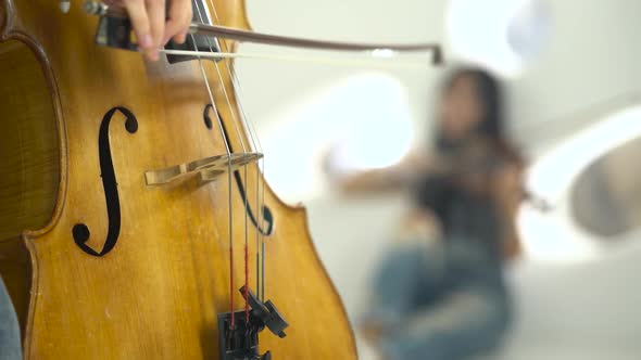 Closeup of a Playing the Cello in the Background Playing the Violin