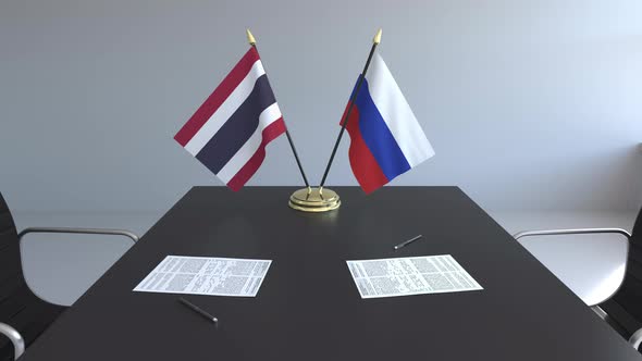 Flags of Thailand and Russia and Papers on the Table